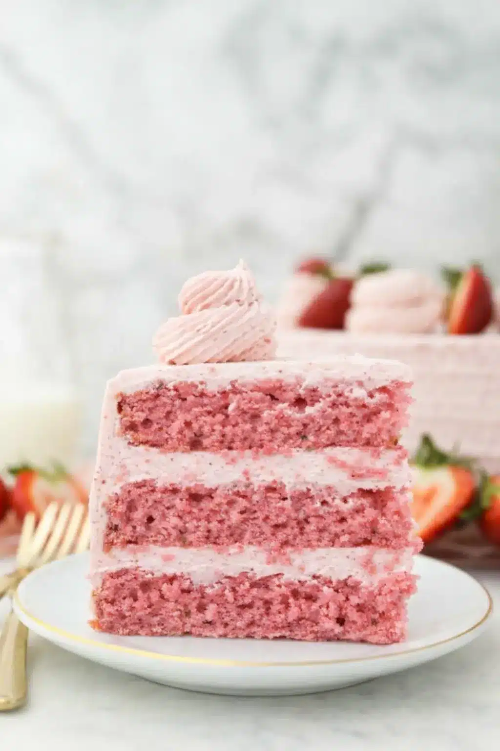 Slice of strawberry cake with strawberry frosting on a plate