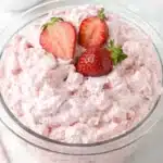Strawberry fluff salad in glass bowl topped with fresh strawberries