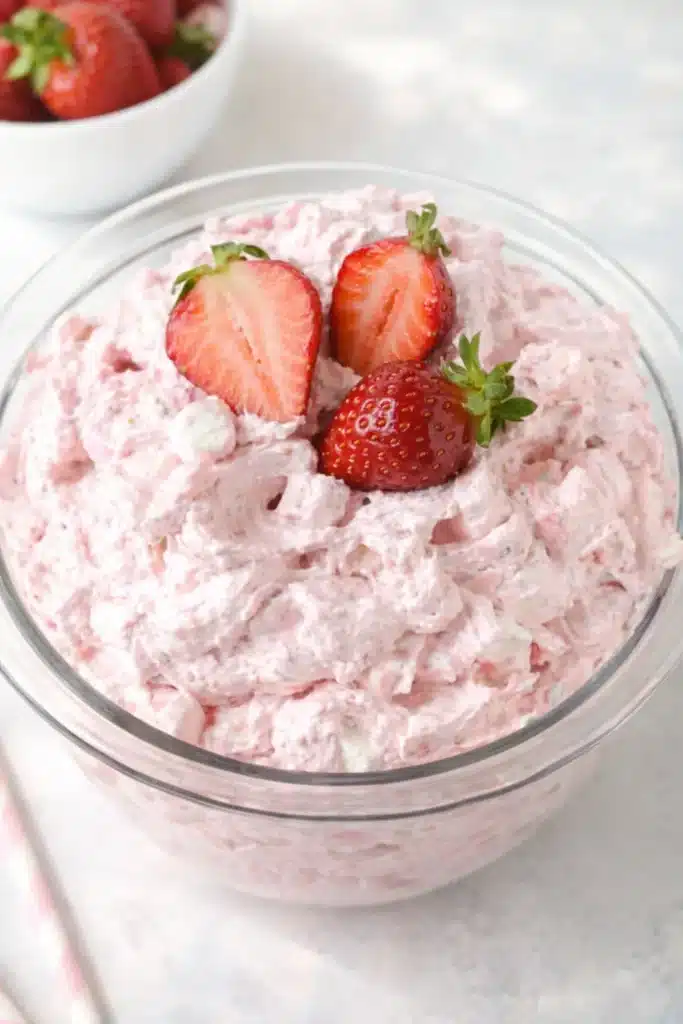 Strawberry fluff salad in glass bowl topped with fresh strawberries