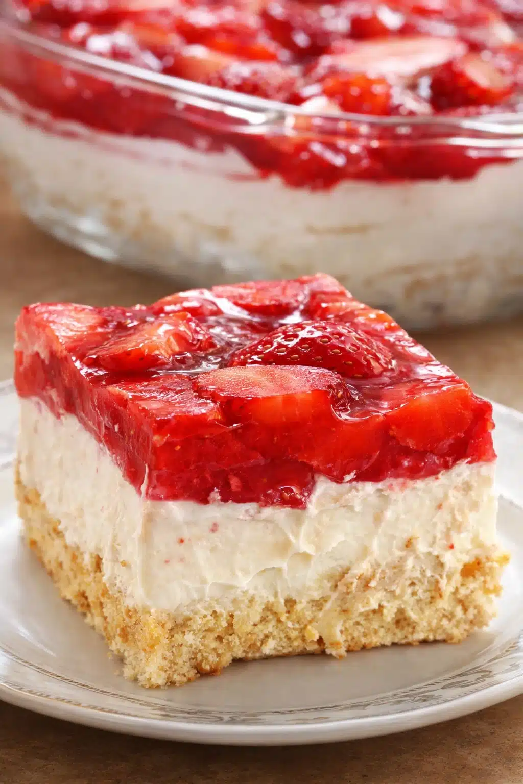 Slice of Strawberry Heaven Cake with cream and strawberry glaze on white plate