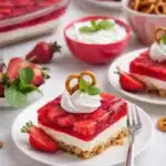 Strawberry pretzel dessert slice with whipped cream and mint on white plate