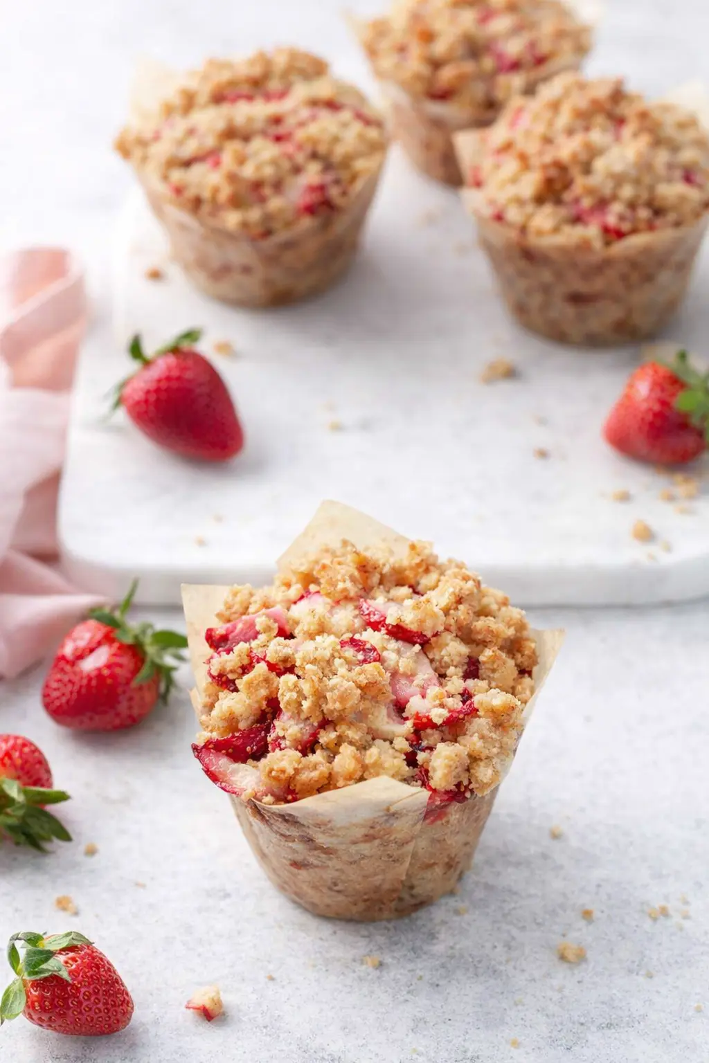 Strawberry rhubarb muffins with brown sugar streusel on light surface