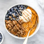 Sweet potato breakfast bowl with yogurt, berries, granola and nut butter drizzle