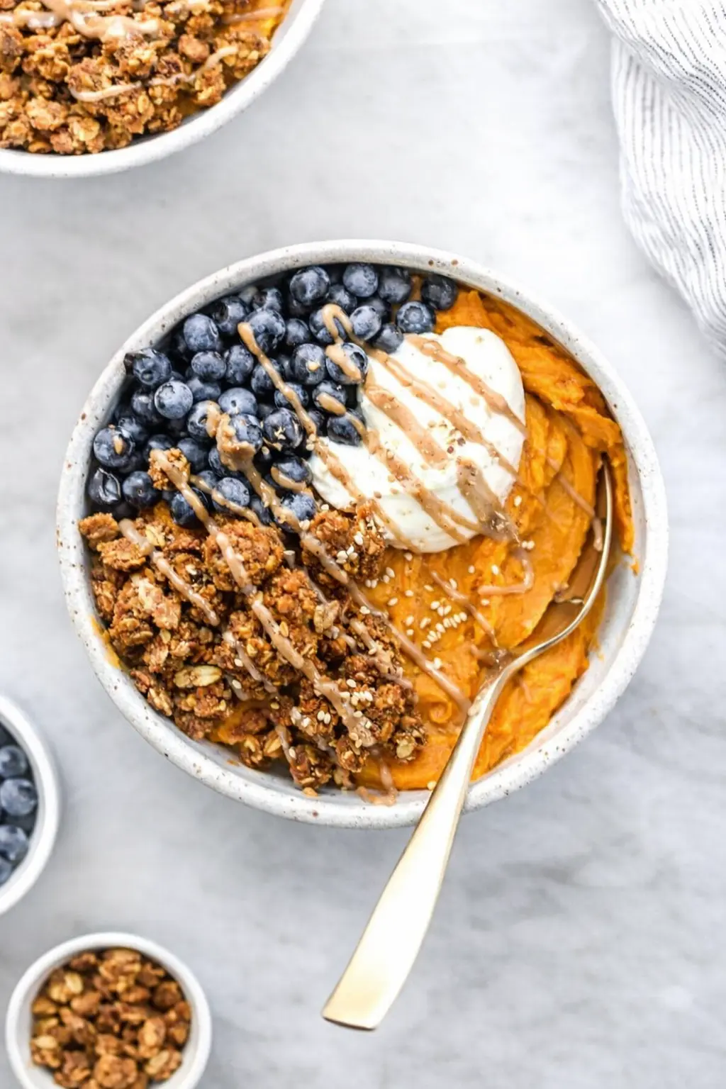 Sweet potato breakfast bowl with yogurt, berries, granola and nut butter drizzle