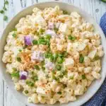 Creamy deviled eggs pasta salad with paprika and green onions in a white bowl