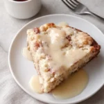 Warm rhubarb cake slice with butter sauce on ceramic plate