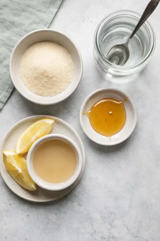 gelatin trick recipe ingredients flat lay with unflavored gelatin, honey, lemon, and water