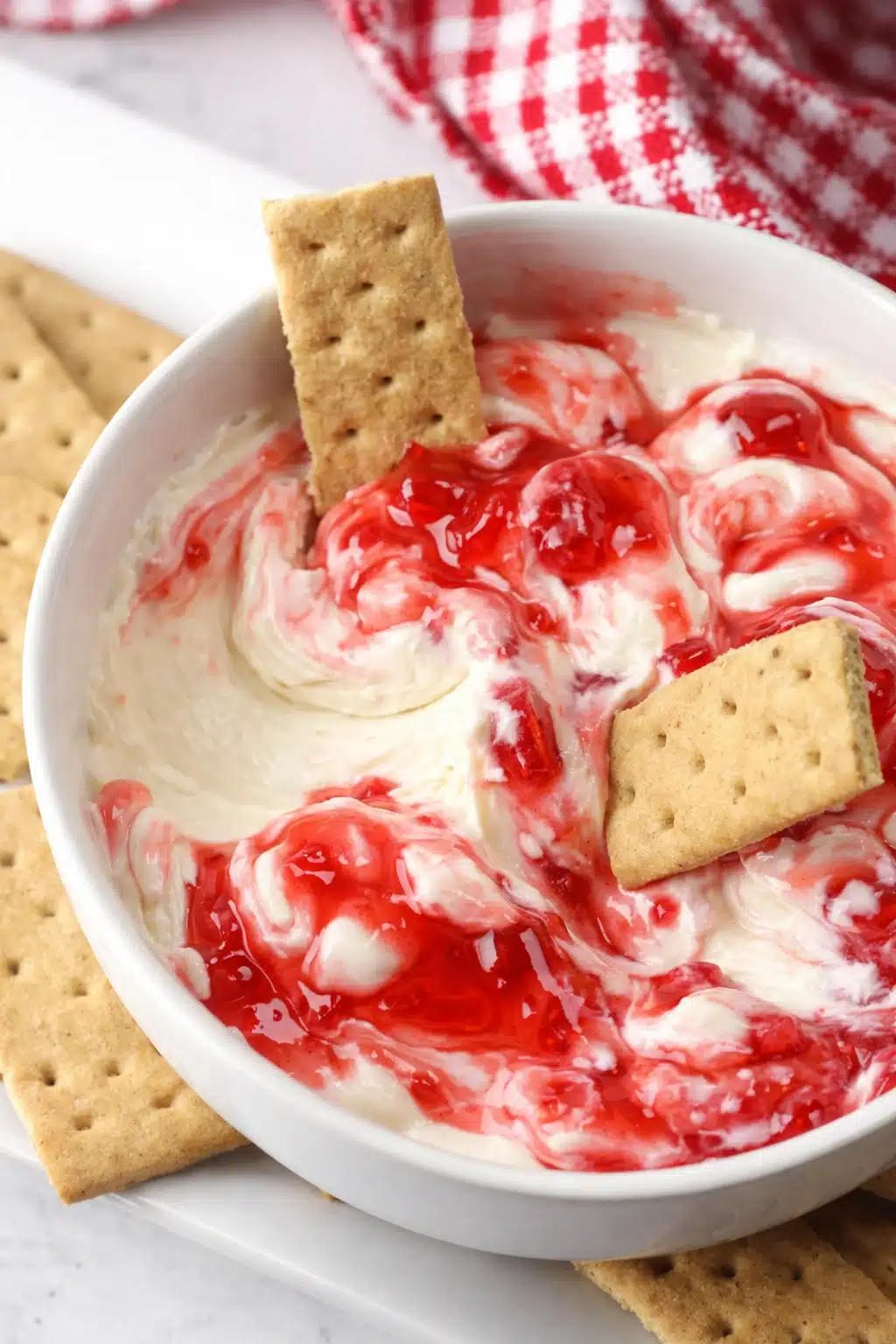 Strawberry cheesecake dip with graham crackers in white bowl