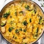 Cheesy broccoli chicken casserole with rice and melted cheddar in a skillet