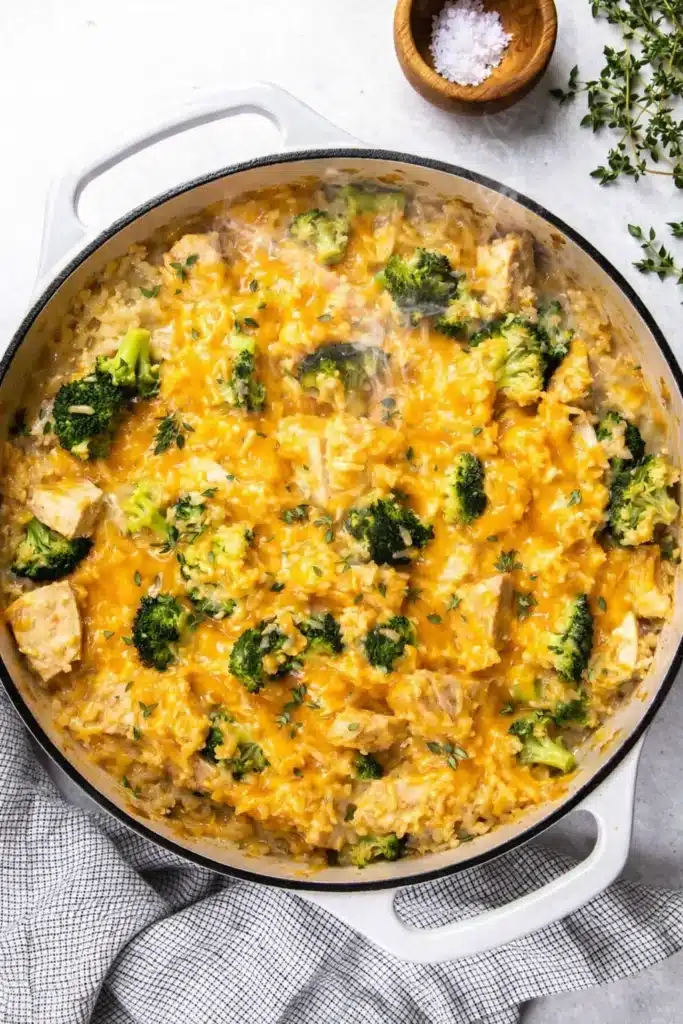 Cheesy broccoli chicken casserole with rice and melted cheddar in a skillet