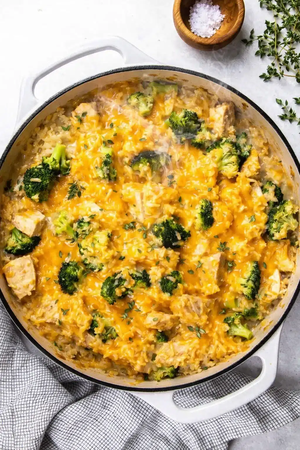 Cheesy broccoli chicken casserole with rice and melted cheddar in a skillet