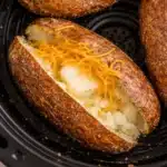 Air fryer baked potato with crispy skin and fluffy inside topped with melting butter
