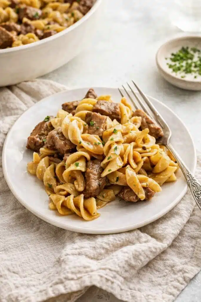 Beef tips and noodles with gravy served on a white plate
