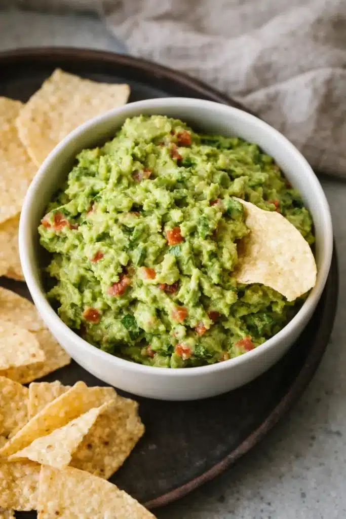 Chunky homemade guacamole dip in a bowl with crispy tortilla chips