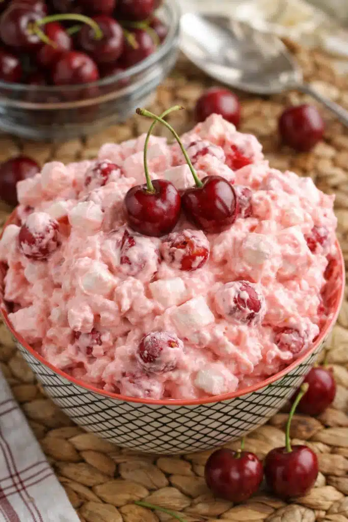 Cherry cheesecake fluff dessert in bowl topped with fresh cherries and marshmallows