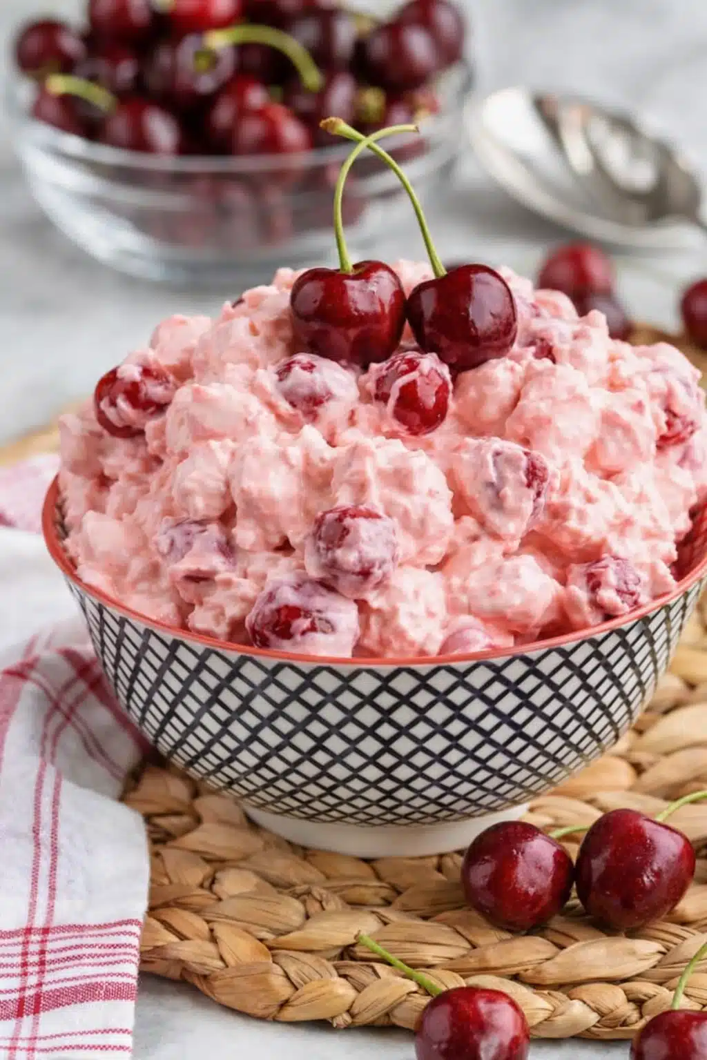 Cherry cheesecake fluff dessert in a bowl topped with fresh cherries and creamy pink texture