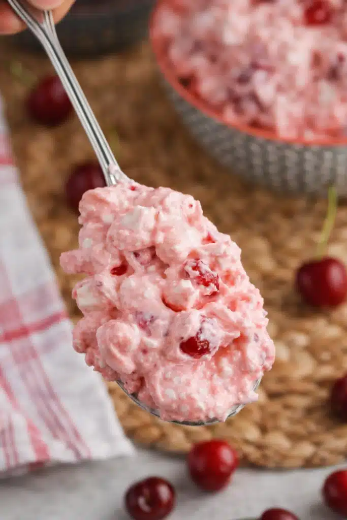 Spoonful of cherry cheesecake fluff showing creamy pink texture with cherries and marshmallows