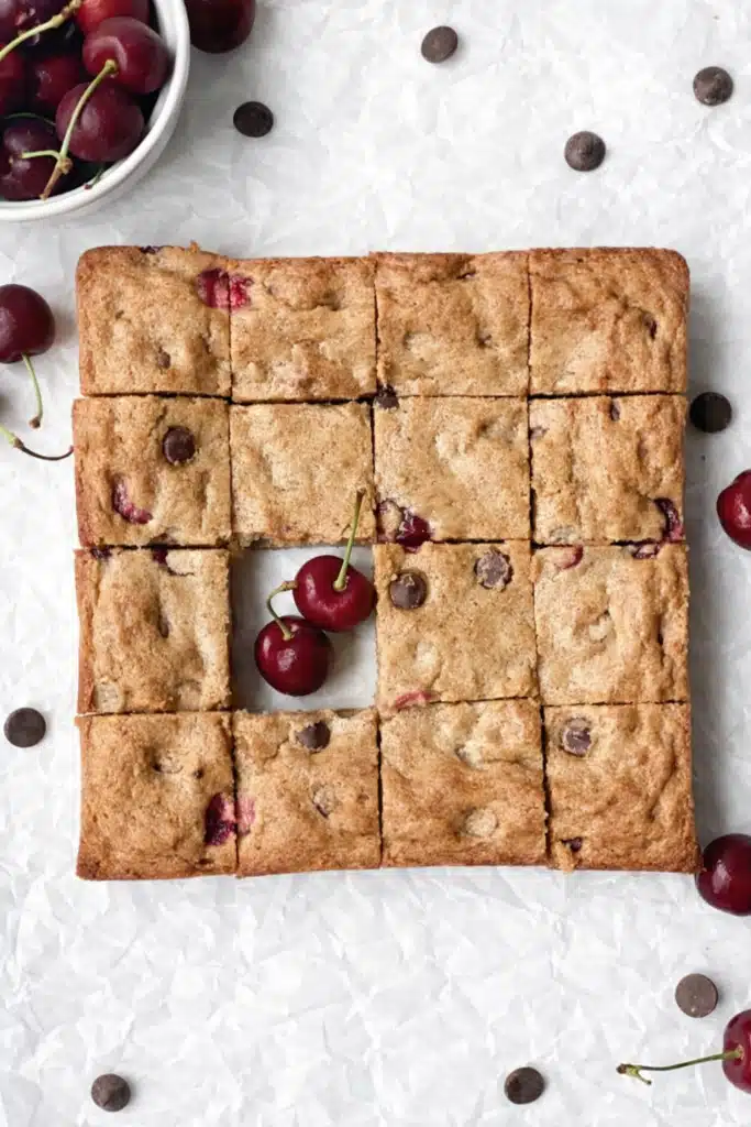 Cherry chocolate chip blondies cut into squares with fresh cherries in the center