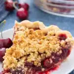 Cherry crumble pie slice with oat crumble topping and juicy cherry filling on white plate