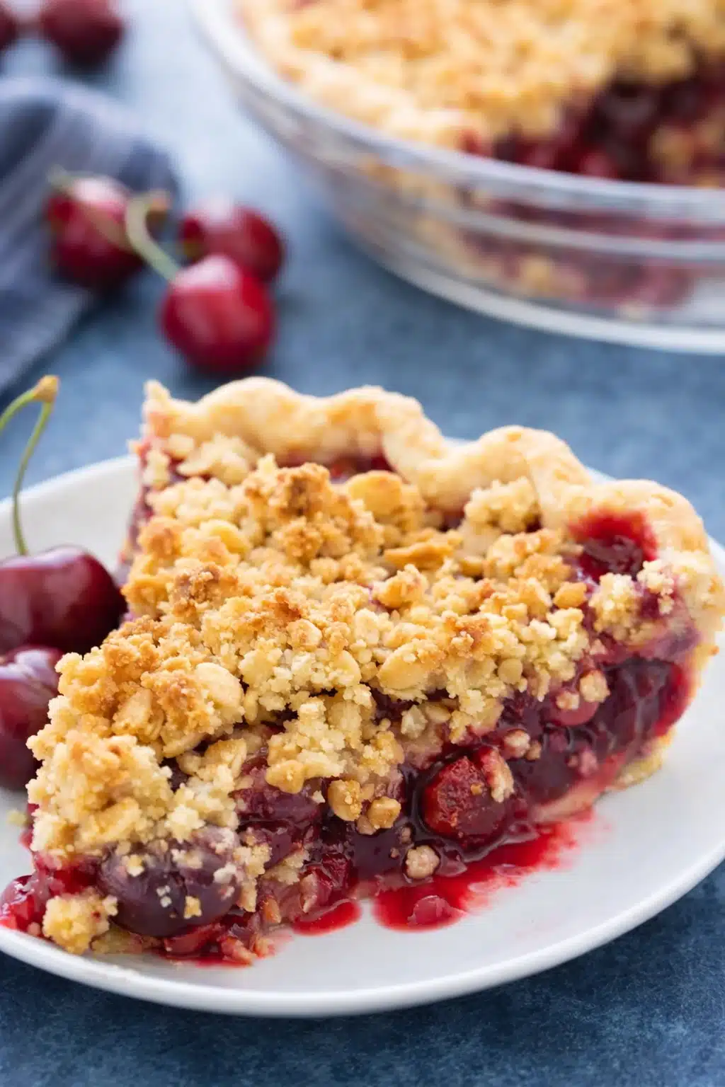 Cherry crumble pie slice with oat crumble topping and juicy cherry filling on white plate