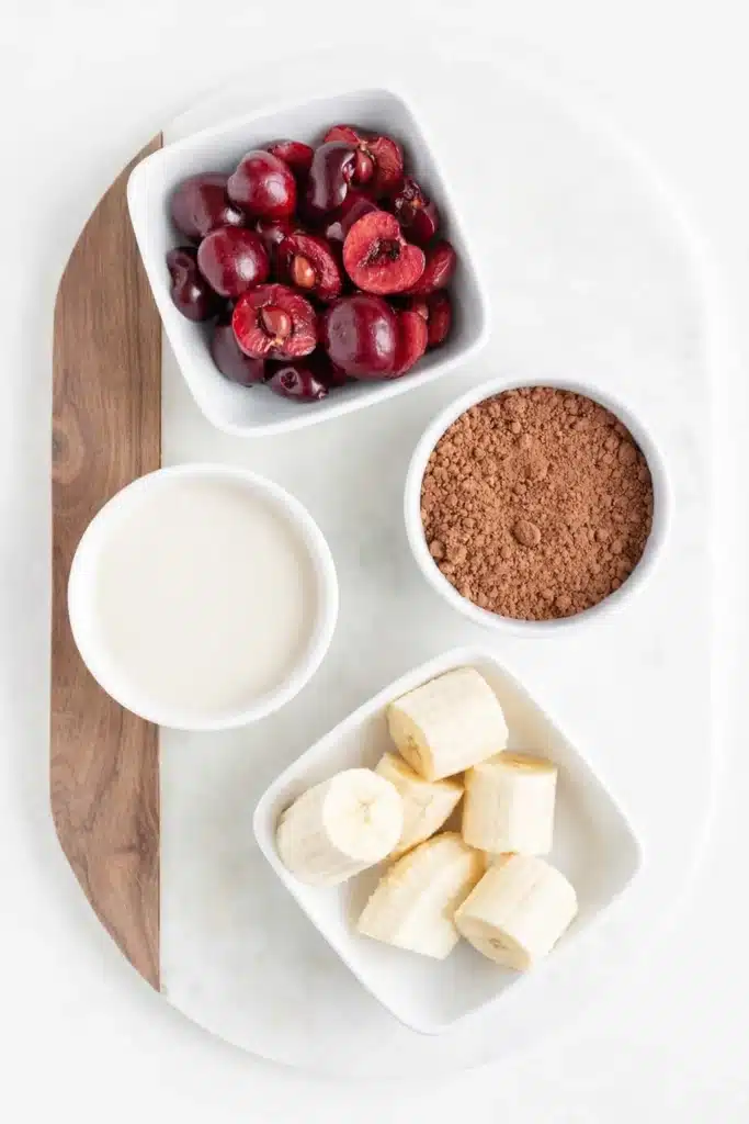 Chocolate Cherry Smoothie Bowl ingredients including cherries, banana, cocoa powder and almond milk