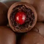 Chocolate covered cherry brownie bomb cut open showing a bright cherry center inside fudgy brownie filling