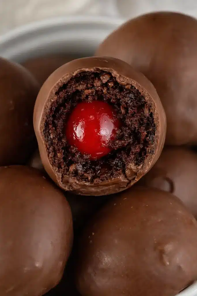 Chocolate covered cherry brownie bomb cut open showing a bright cherry center inside fudgy brownie filling