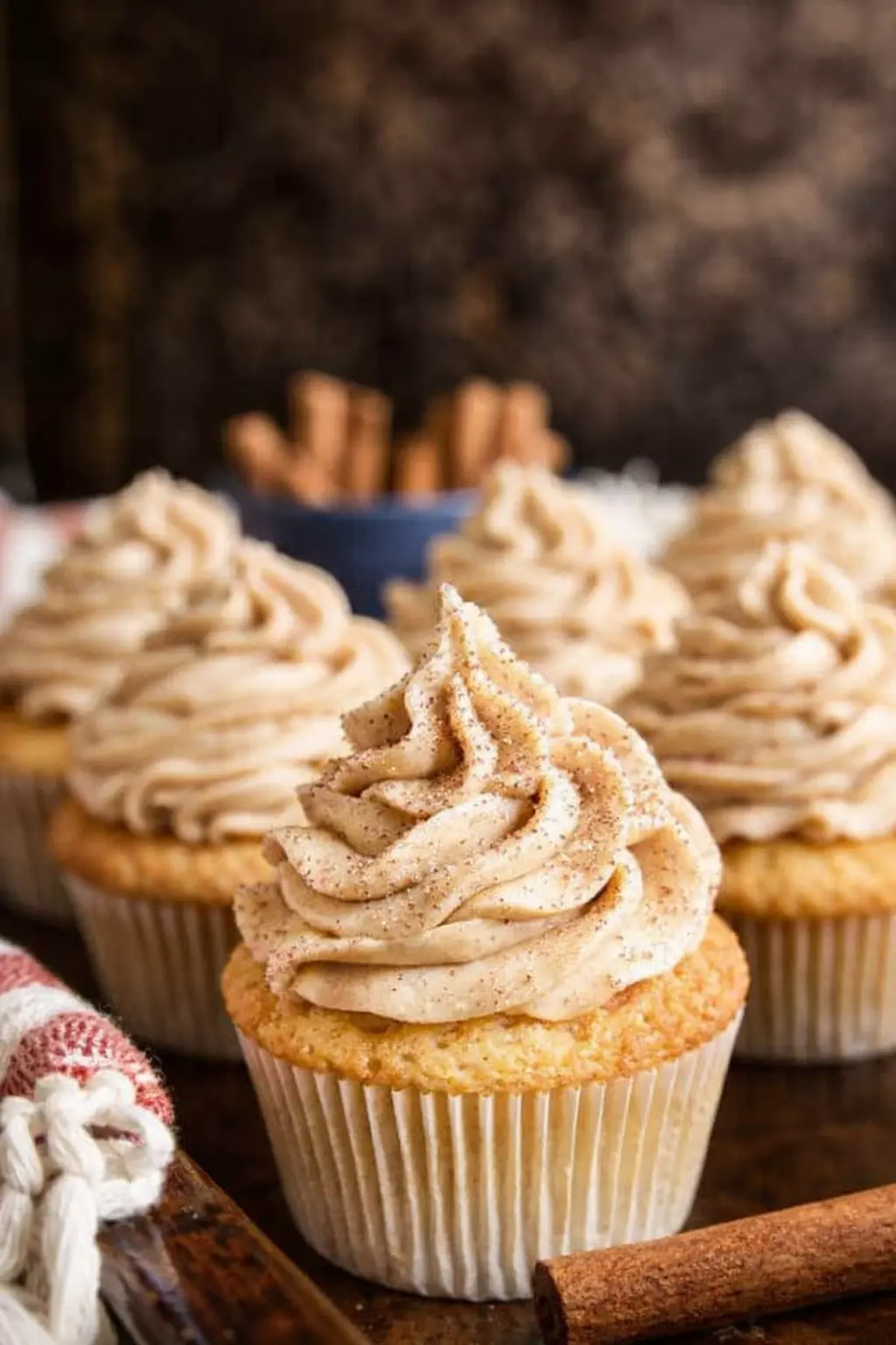 Churro cupcakes with cinnamon frosting and cinnamon sugar on a rustic surface