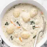 Creamy chicken gnocchi soup with shredded chicken, spinach, carrots, and potato gnocchi in a white bowl
