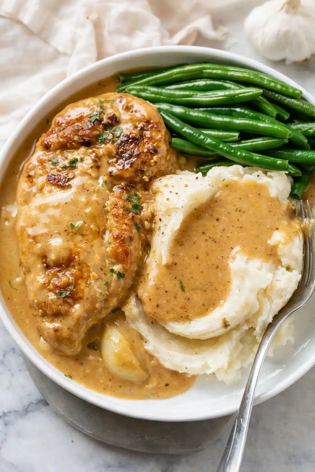 Creamy garlic chicken with mashed potatoes and green beans in rich garlic cream sauce