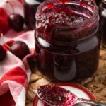 Homemade cherry vanilla jam in glass jar with spoon and fresh cherries on rustic table