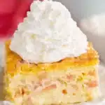 Easy rhubarb custard cake slice with whipped cream on a dessert plate