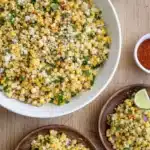 Elote corn salad with cotija cheese, cilantro, lime, and chili powder in a bowl
