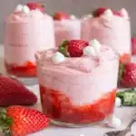Fresh strawberry mousse layered with strawberry puree in a glass dessert cup topped with fresh strawberries