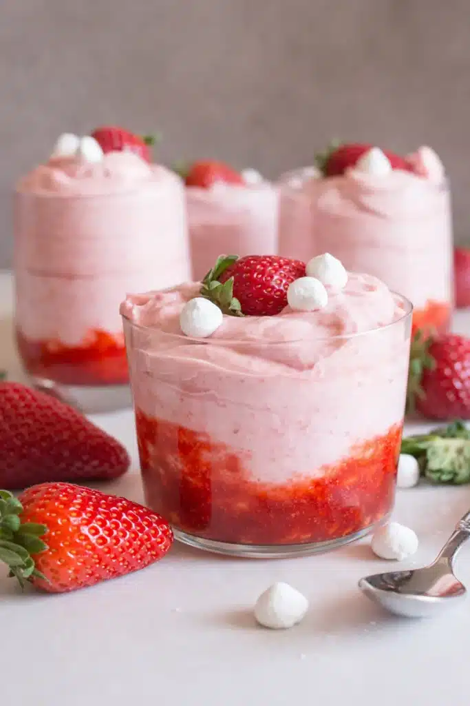 Fresh strawberry mousse layered with strawberry puree in a glass dessert cup topped with fresh strawberries