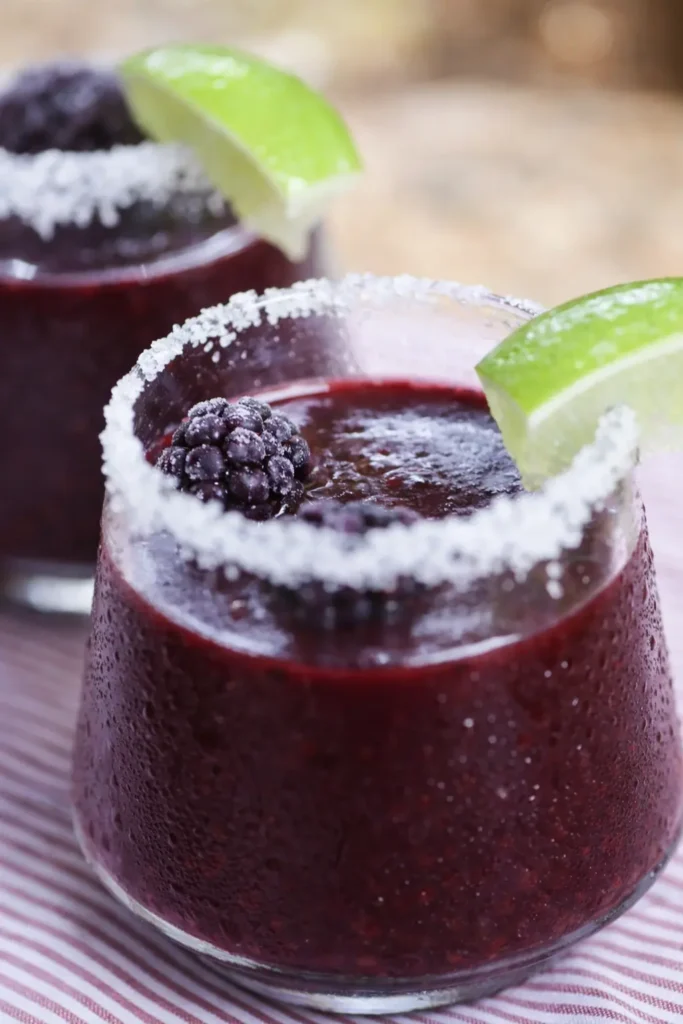 Frozen Blackberry Margarita with lime wedge and salted rim in a chilled cocktail glass