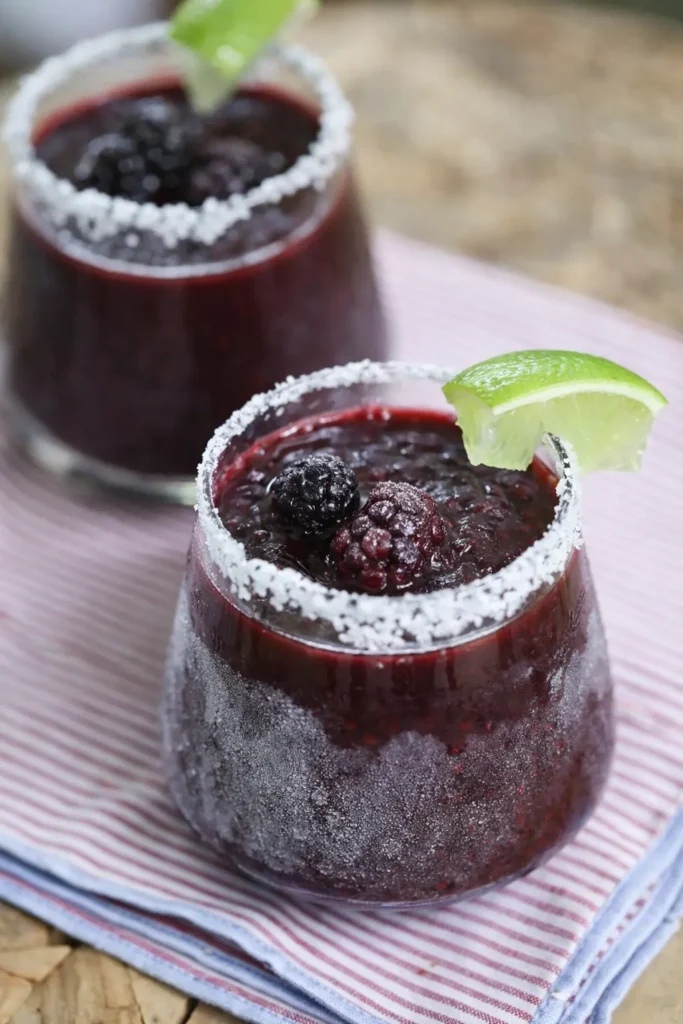 Frozen Blackberry Margarita with salted rim, lime wedge, and fresh blackberries