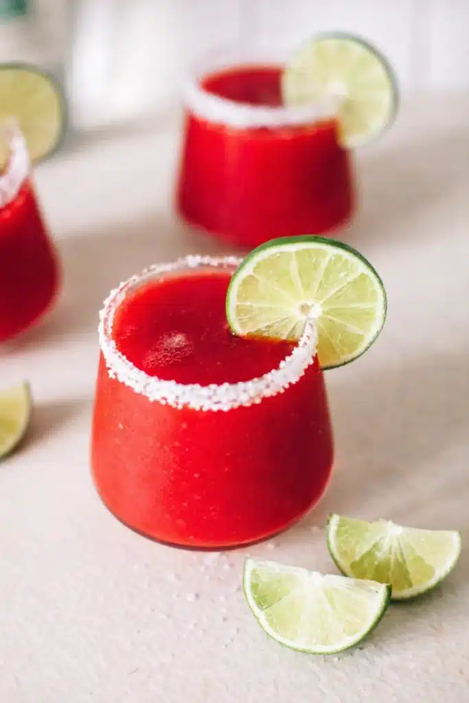 Frozen Strawberry Margarita with salted rim and lime garnish in a bright cocktail glass
