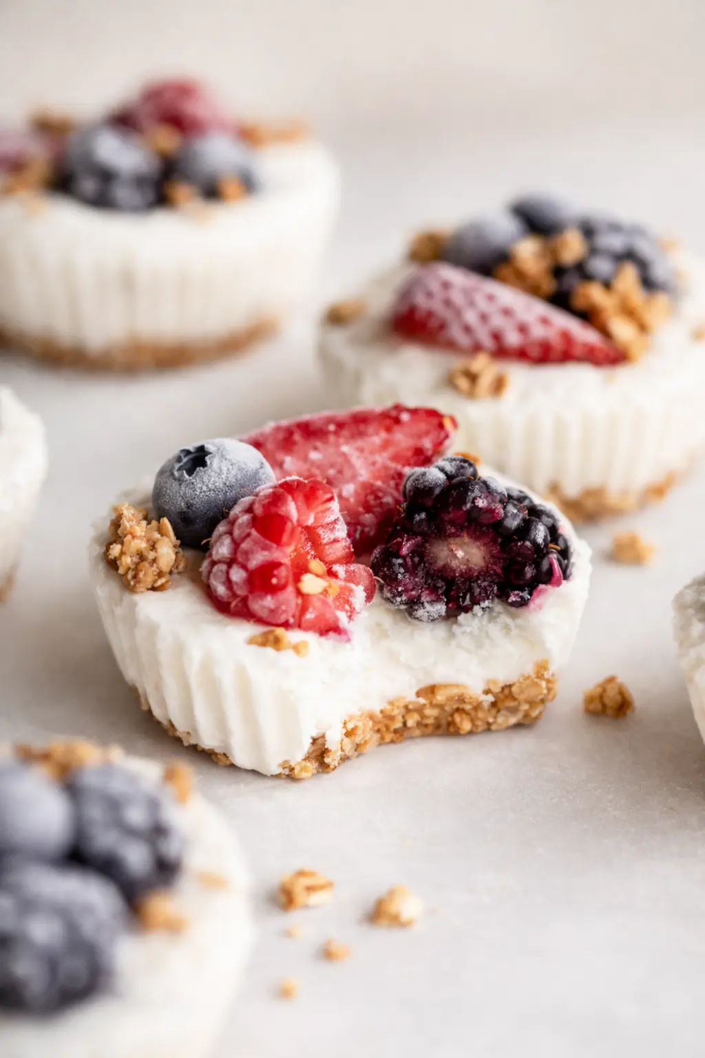 Frozen yogurt granola cups with berries and crunchy oat crust on a light background