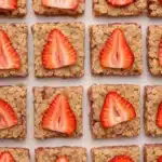 Healthy strawberry oatmeal bars topped with fresh strawberry slices arranged in a grid