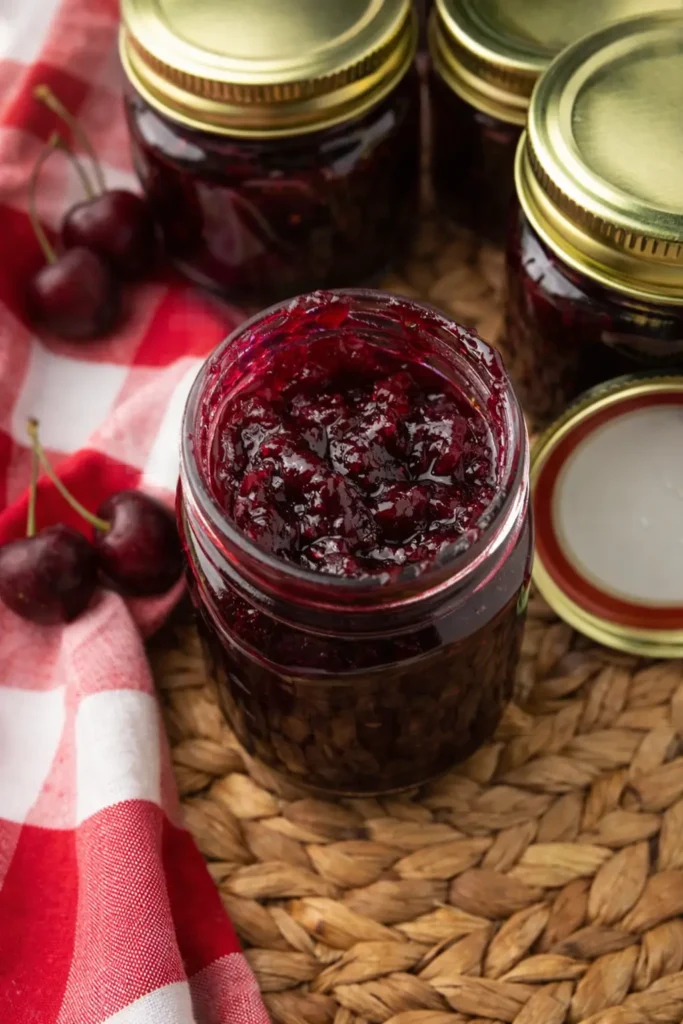 Easy Cherry Vanilla Jam in glass jar with fresh cherries and homemade jam jars
