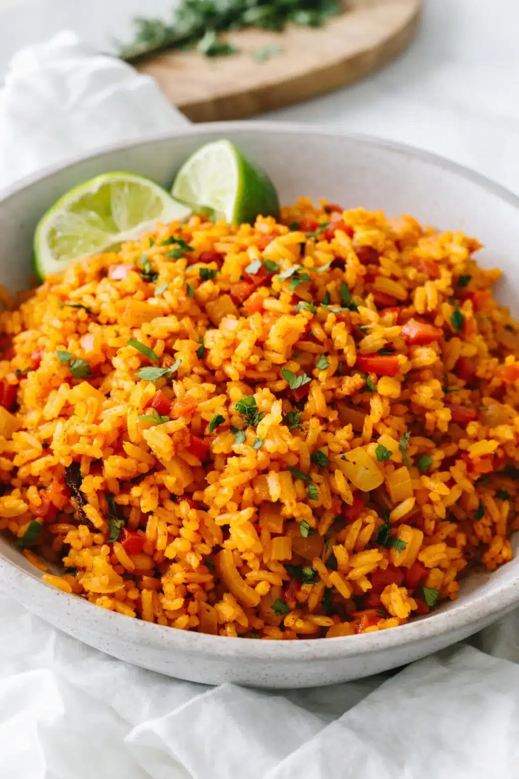 Fluffy Mexican rice with tomato, vegetables, cilantro, and lime wedges in a ceramic bowl