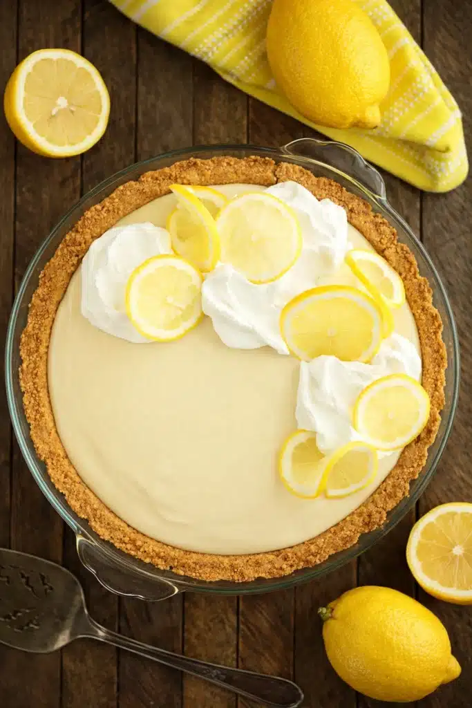 Lemon cream pie with whipped cream and lemon slices in graham cracker crust