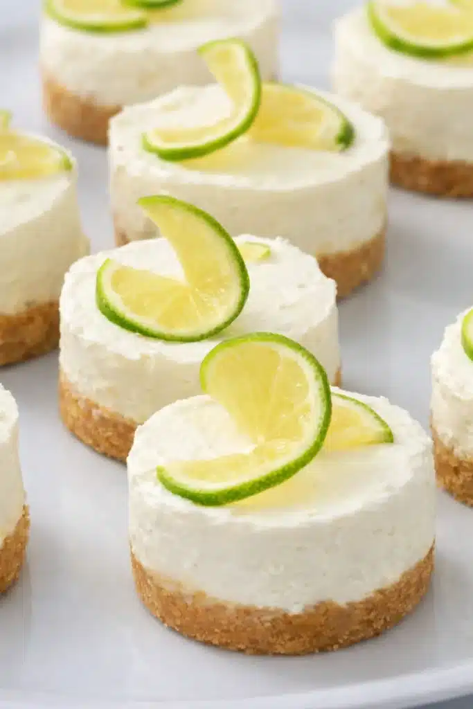 Mini margarita cheesecakes with lime slices and graham cracker crust on serving plate