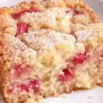 Moist rhubarb cake slice with powdered sugar and tender pink rhubarb pieces