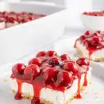 No bake cherry delight slice with graham cracker crust and creamy cheesecake filling topped with glossy cherry pie filling