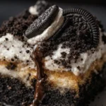 Oreo dump cake slice with whipped cream, chocolate drizzle, and Oreo cookies on top