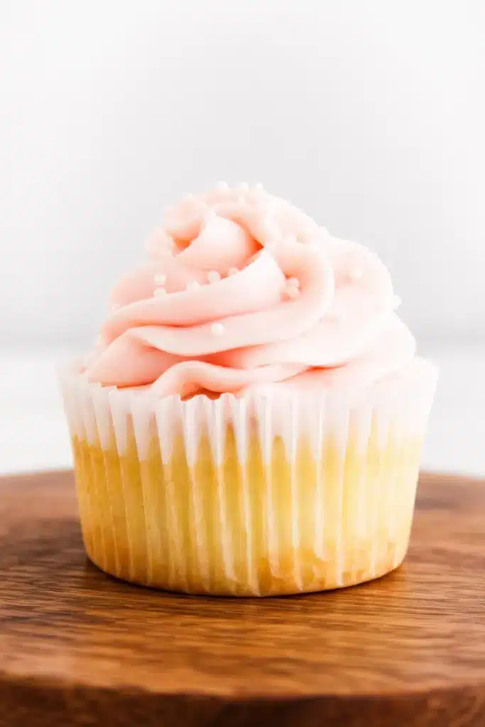 Rhubarb Honey Cupcakes with pink buttercream on a wooden board