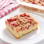 Rhubarb Streusel Cake Recipe That Feels Wonderful 5 Rhubarb streusel cake slice with crumb topping on a plate and baking dish in the background