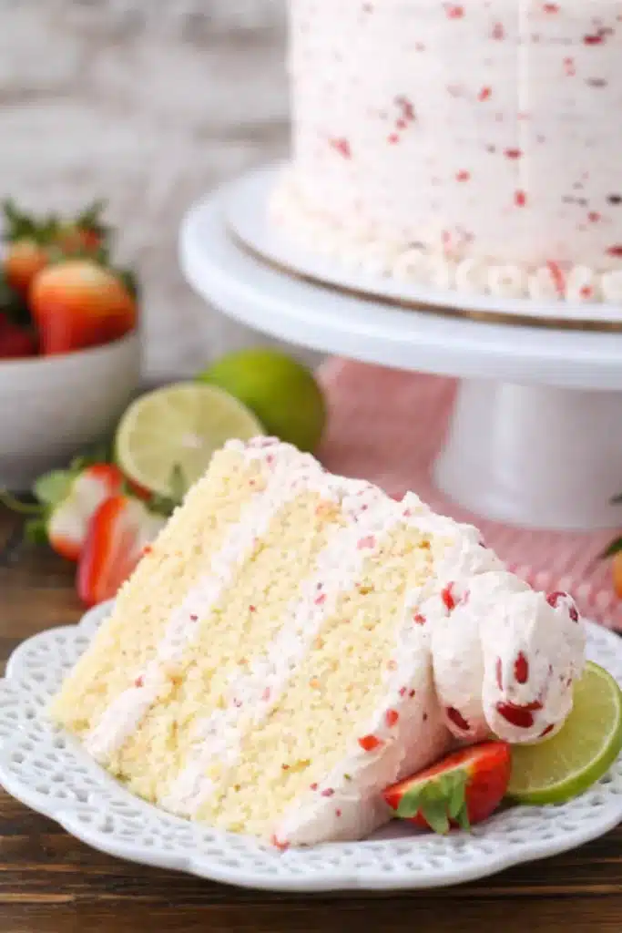 slice of strawberry margarita layer cake with strawberry buttercream and lime garnish